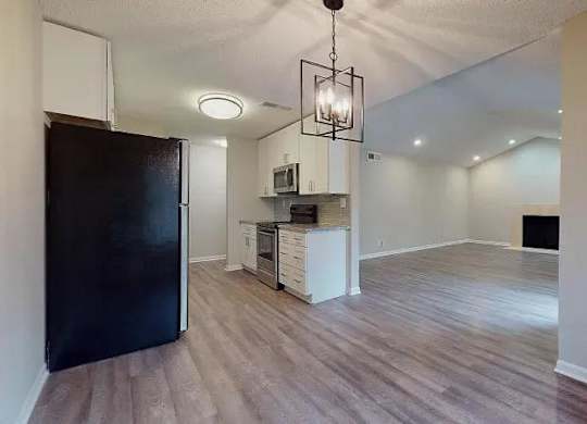 A kitchen area with a black refrigerator and a wooden floor. at Spalding Vue, Peachtree Corners, 30092