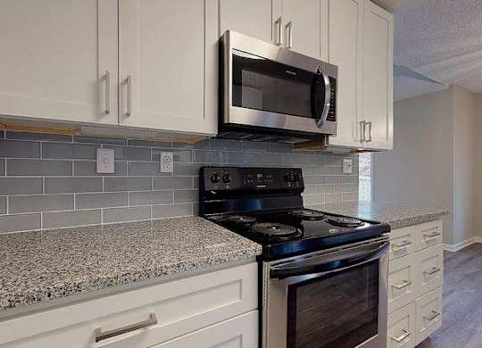 A kitchen with a black stove top oven and a microwave above it. at Spalding Vue, Peachtree Corners, 30092