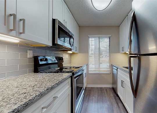 A kitchen with a stove top oven and a microwave above it. at Vue on Medlock, Peachtree Corners, Georgia