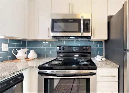A kitchen with a black stove top oven and a black refrigerator. at Cumberland Pointe, Georgia, 30080