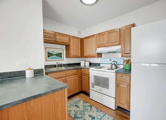 A kitchen with wooden cabinets and a white refrigerator at Fullerton Court Apartments, Chicago, IL 60614
