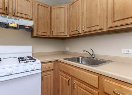 A white gas stove is in a kitchen with wooden cabinets at Sheridan Park, Chicago, IL