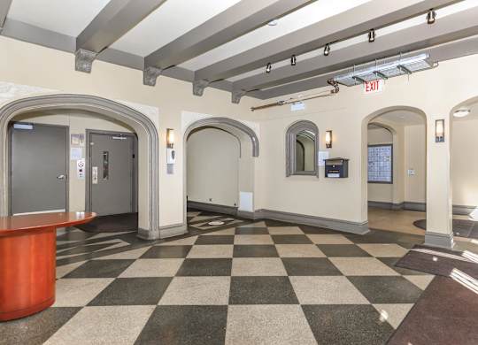A hallway with a black and white checkered floor and a red reception desk at Sheridan Park, Chicago, 60640