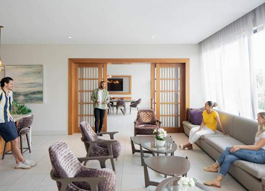 A man in a striped shirt is standing in a living room with two women sitting on a couch. at Palma, Florida