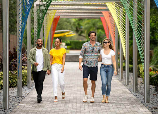 Four people walking on a bridge with a metal structure. at Palma, Doral, 33166