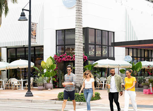 Four people are walking across a crosswalk. at Palma, Doral, Florida