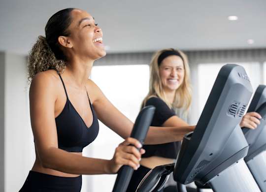 Two women are exercising on treadmills in a brightly lit room. at Palma, Florida