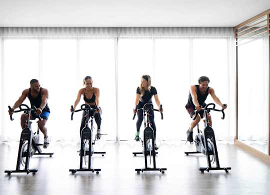 Four people are riding stationary bikes in a row. at Palma, Doral, 33166