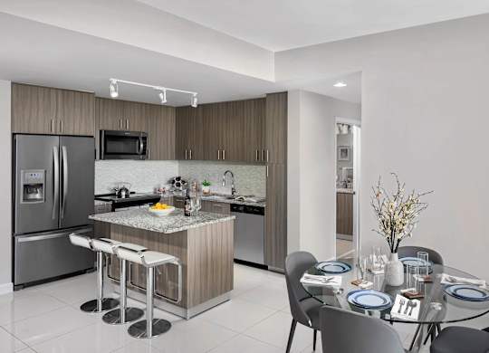 A modern kitchen with a dining table at Palma, Doral, Florida