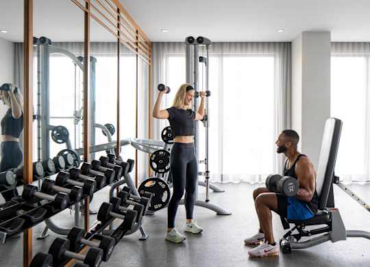 A man and woman are working out in a gym with various exercise equipment. at Palma, Doral, 33166