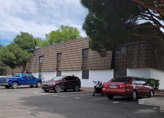 A parking lot with cars and a building in the background.