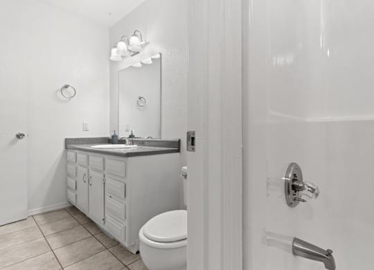 A white bathroom with a toilet, sink, and mirror.