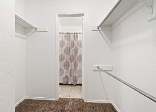 A white hallway with a brown carpet and a doorway leading to a bathroom.