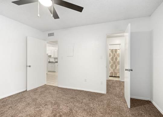 A room with a ceiling fan and carpeted floor.