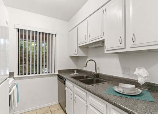 A kitchen with white cabinets and a granite countertop.