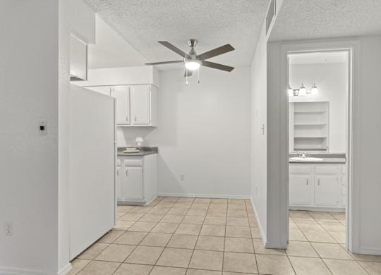 A white kitchen with a fan on the ceiling.