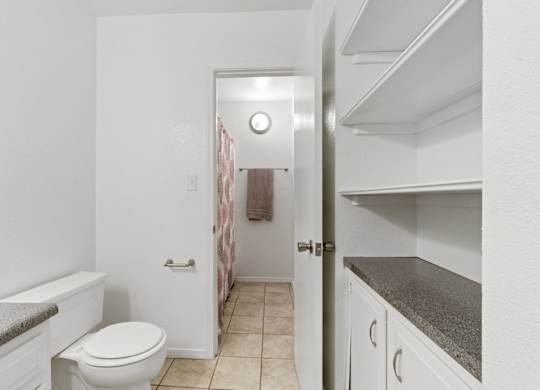 A white toilet sits in a small bathroom next to a white bathtub.
