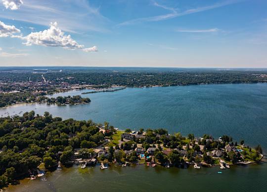 A small island with houses and boats surrounded by water. at The Grove  Apartments, Orillia, ON
