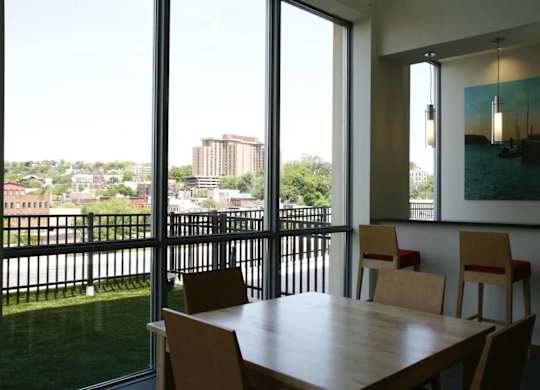 A table with chairs in front of a window with a view of a city.at 66 Main, Yonkers, 10701