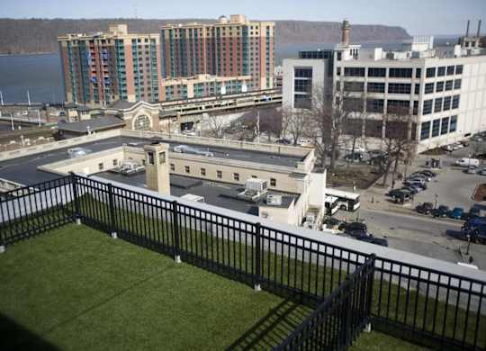 A view of a city from a balcony with a black railing.at 66 Main, New York