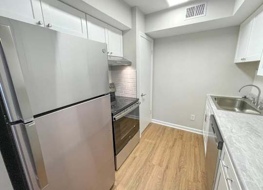 A kitchen with a refrigerator, oven, and sink.