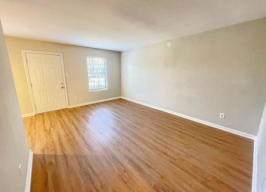 A room with wooden flooring and a white door.