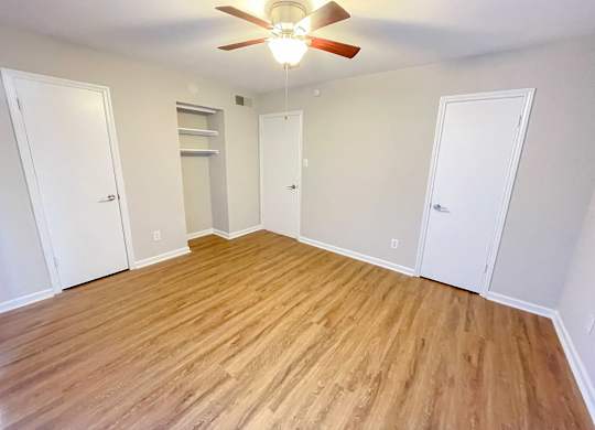 A room with a ceiling fan and wooden flooring.