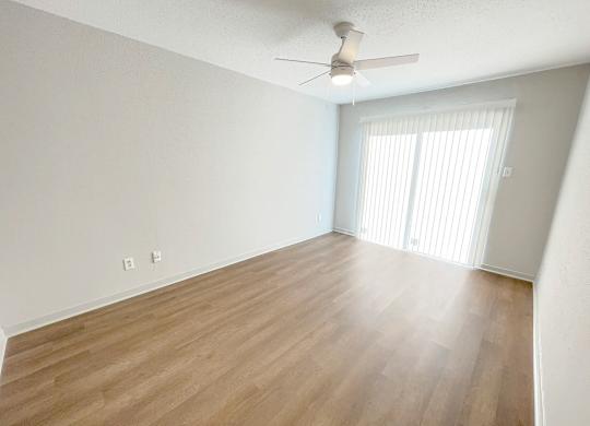 A room with a ceiling fan and wooden flooring.