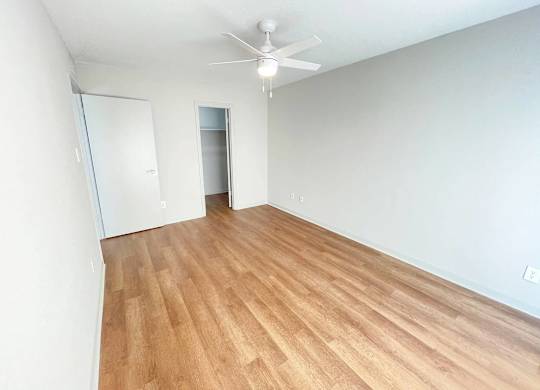 A room with a ceiling fan and wooden flooring.