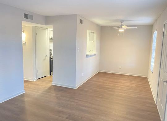 A room with a ceiling fan and light, and a doorway leading to another room.