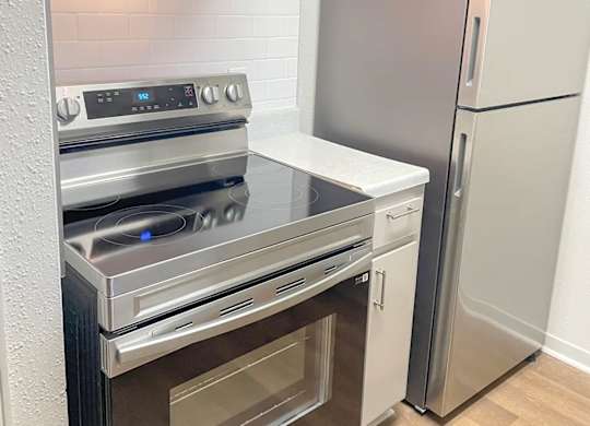 A modern kitchen with a stainless steel refrigerator and oven.
