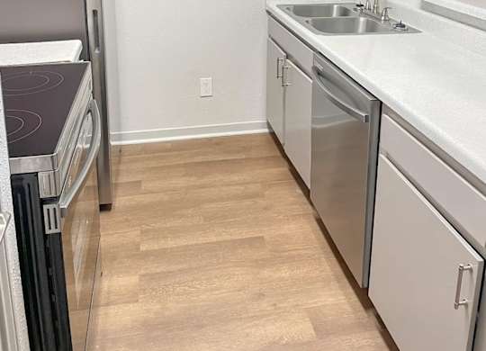 A kitchen with a refrigerator, dishwasher, and sink.