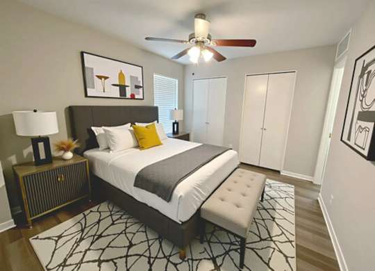 A bedroom with a bed, a ceiling fan, and a rug.