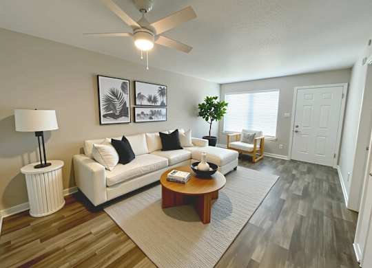 A living room with a white couch, a coffee table, and a ceiling fan.