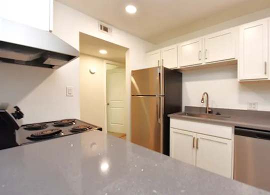A kitchen with white cabinets and a stainless steel refrigerator.