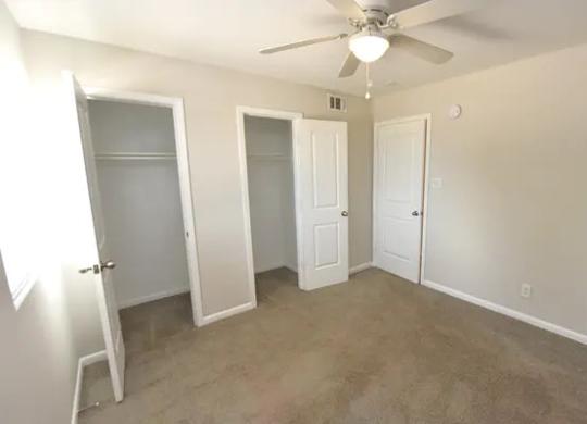 A room with a ceiling fan and three doors.