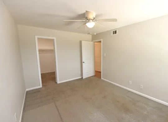 A room with a ceiling fan and a door.