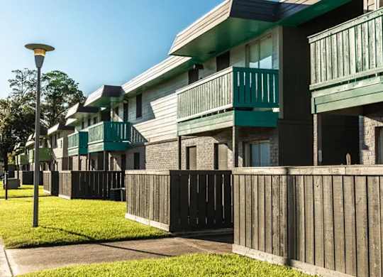 A row of green apartment buildings with balconies and wooden fences.