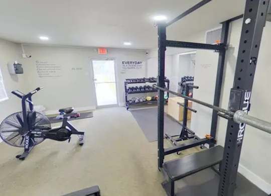 A gym with a rowing machine and weight racks.