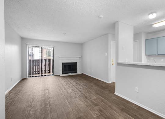 A spacious living room with a fireplace and wood flooring.