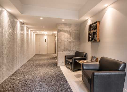 A hallway with a carpeted floor, a stone wall, and a framed picture on the wall.