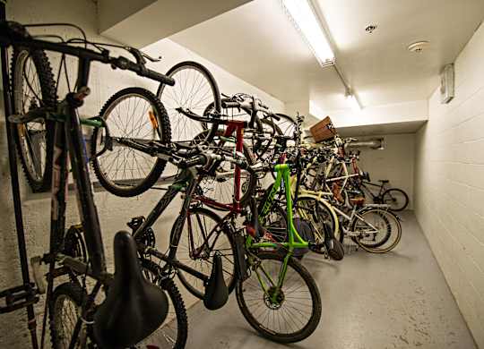 A bike rack full of bicycles in a white hallway.