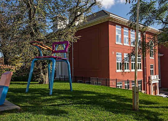 A playground with a blue and purple slide in front of a red building.