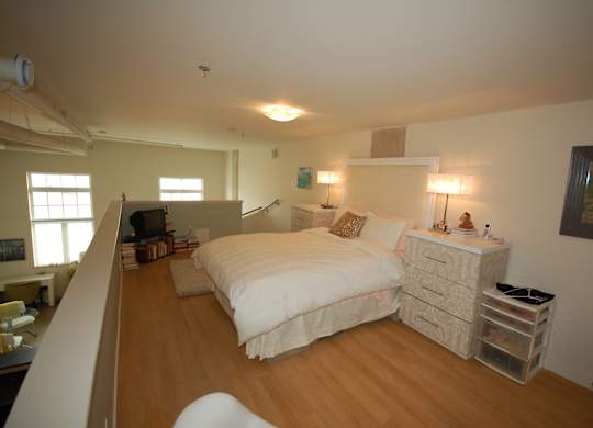 A bedroom with a bed, nightstand, and chair.