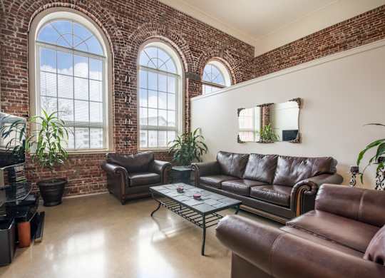 A living room with brown leather couches and a brick wall.