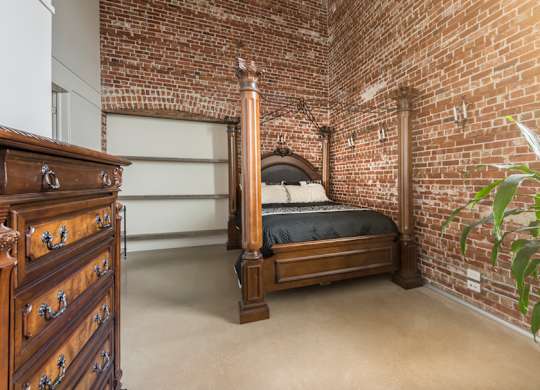 A bedroom with a brick wall and a bed.