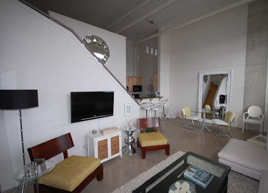 A living room with a white couch, a wooden chair, and a glass coffee table.