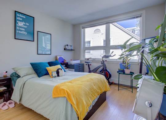 A bedroom with a bed, a chair, and a window.