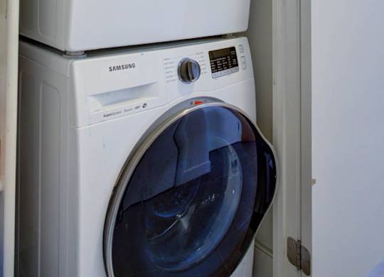 A stack of white washing machines with the top one being a Samsung.