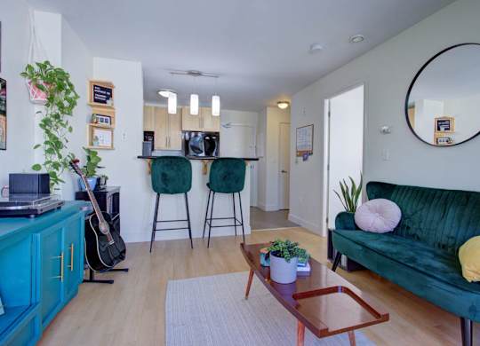 A living room with a green couch, a guitar, and a potted plant.